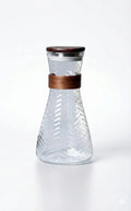 Clear glass carafe with textured pattern, wood band and lid, on white background