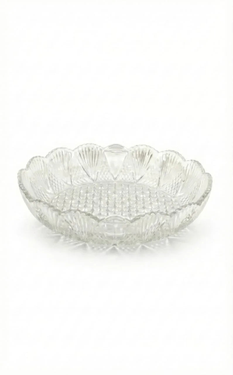 Clear glass decorative plate with scalloped edges on a white background